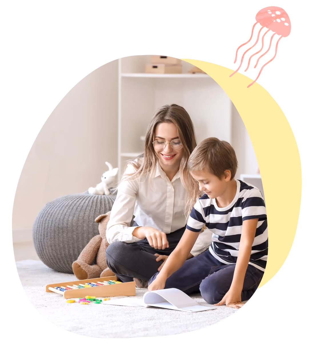 Woman and boy sitting on floor playing with educational toys and paper in a light room.