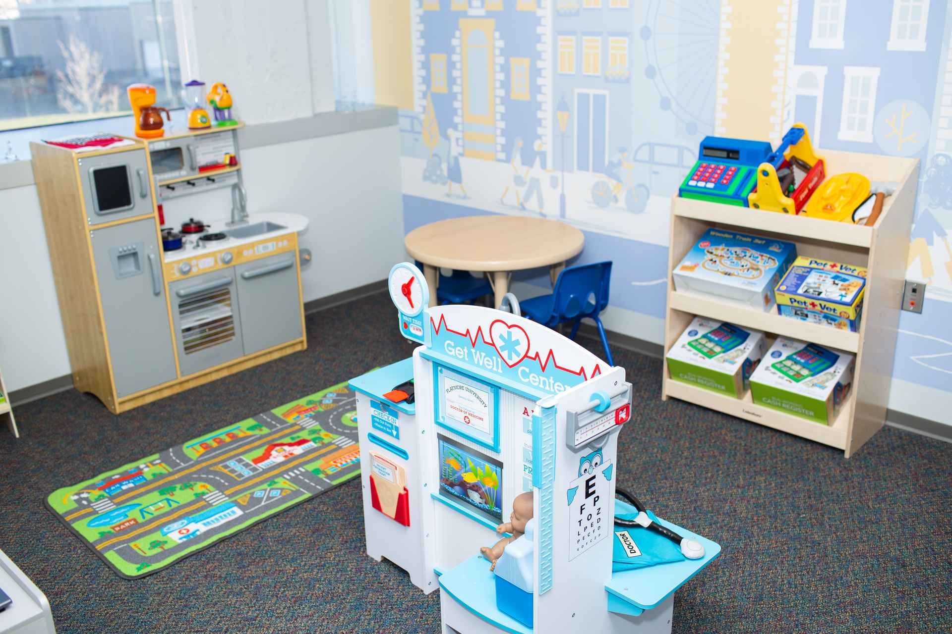 Dramatic play room with pretend doctor's office, play kitchen, and city mural in a center-based ABA therapy clinic