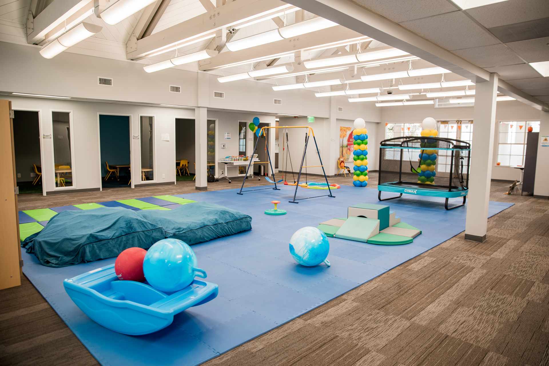 Large gross motor gym with swing set, trampoline, and therapy rooms in an ABA center for autism therapy