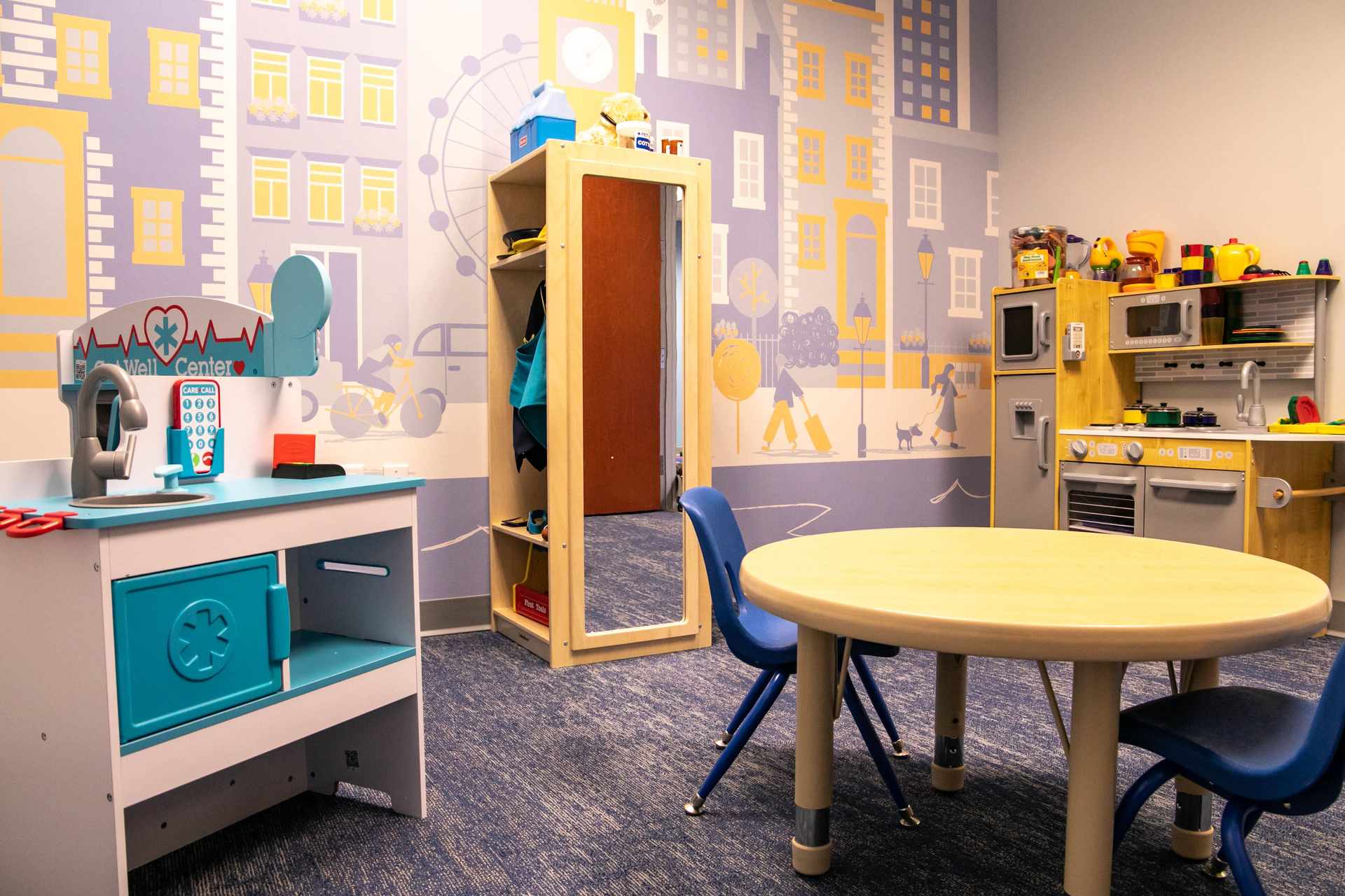 Dramatic play room with superhero figures, dollhouse toys, and dress-up costumes in an autism therapy center