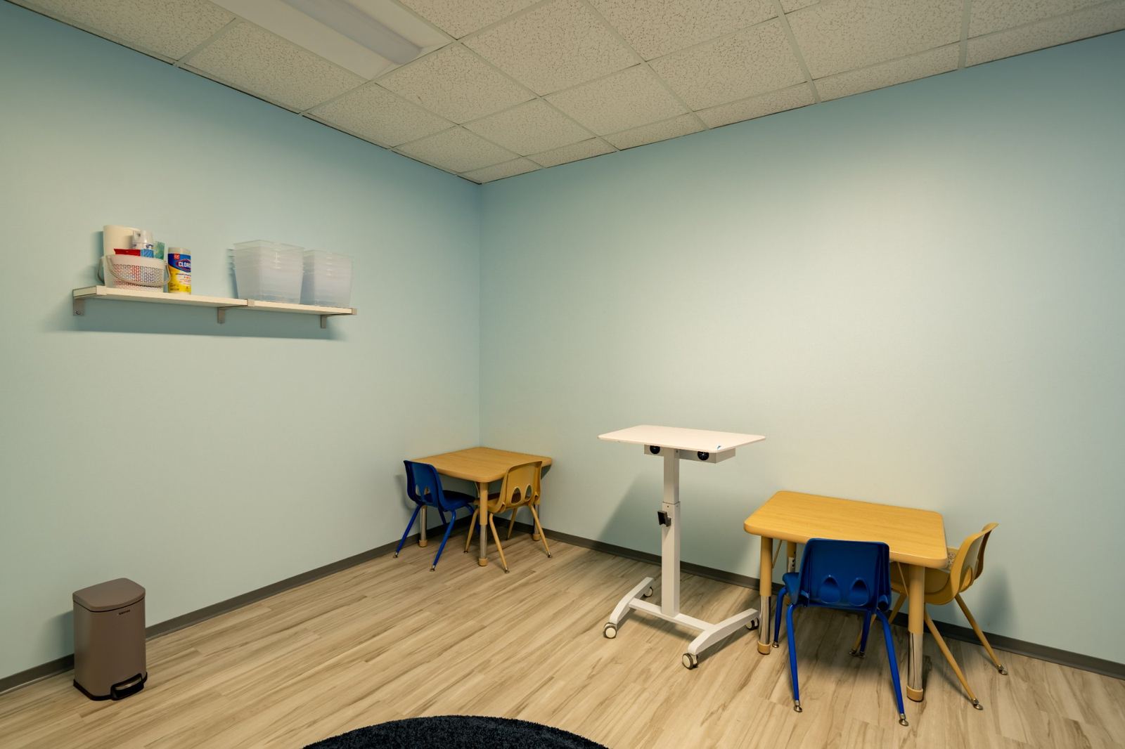 ABA therapy room with child-sized direct therapy tables and BCBA supervisor's desk