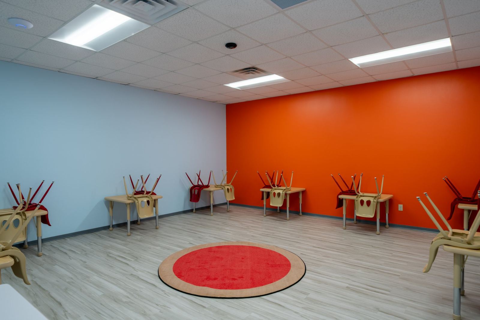 ABA therapy room with child-sized direct therapy tables and a bright orange accent wall