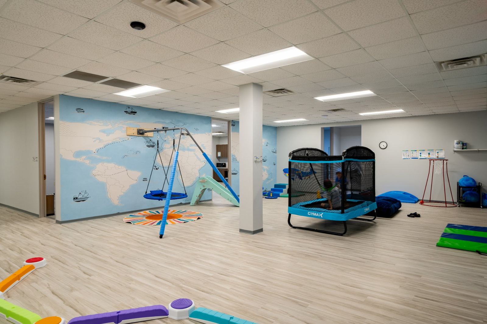 Motor gym room with a swing, slide, trampoline and balance beams for movement and regulation skill-building