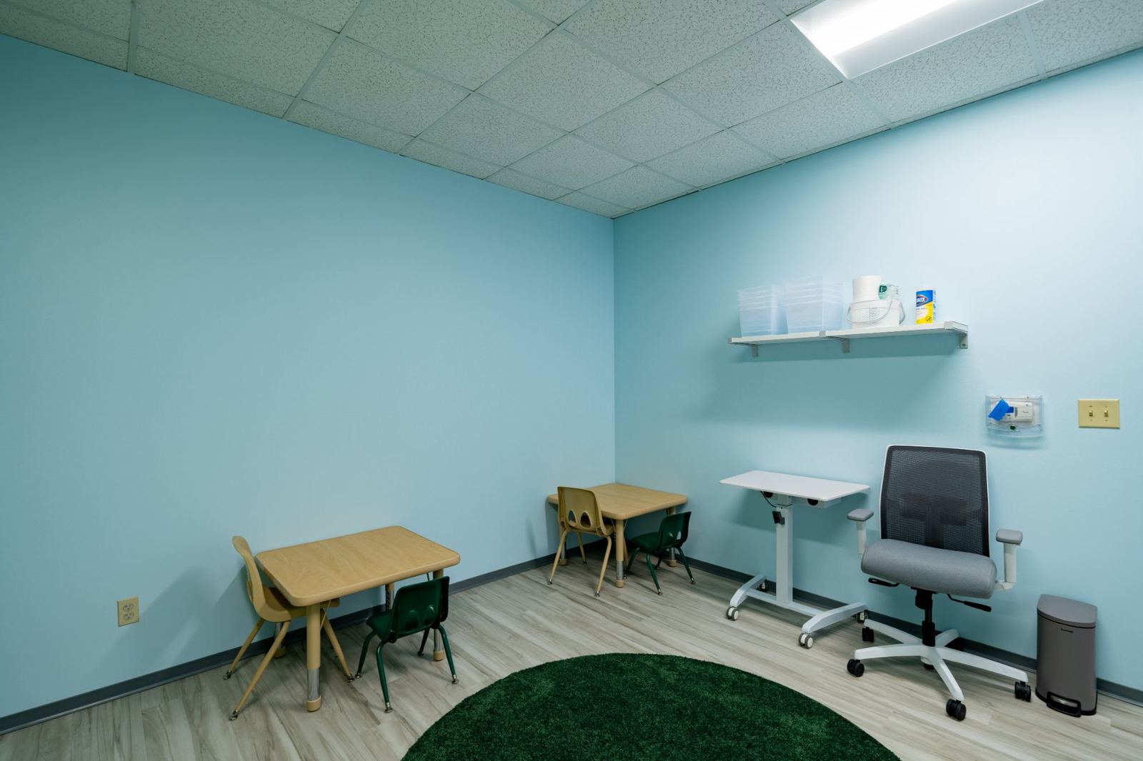 One-to-one autism therapy room with calming blue walls and two child-sized tables