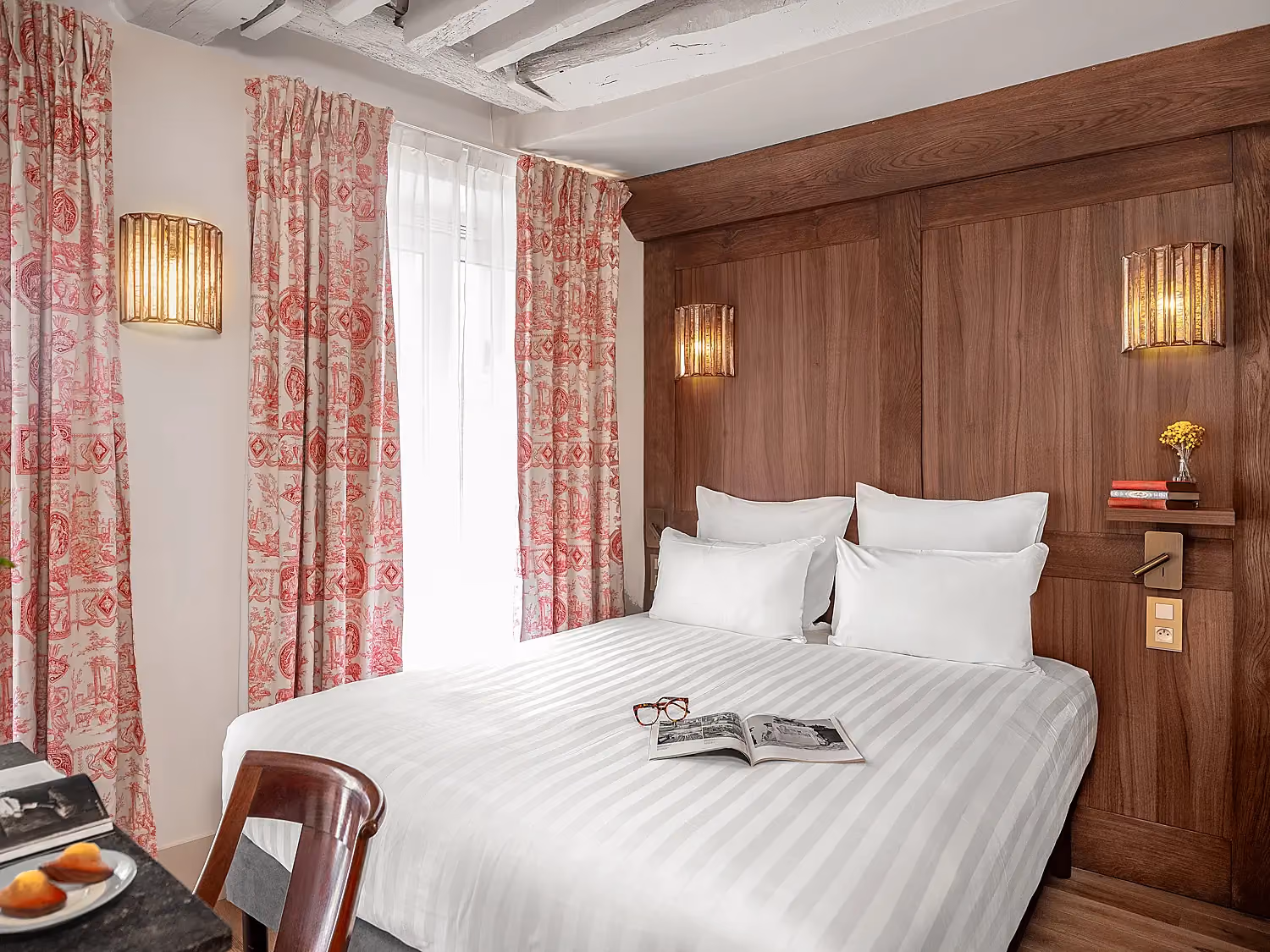 Lit double confortable dans une suite hôtelière aux accents de bois chaleureux.