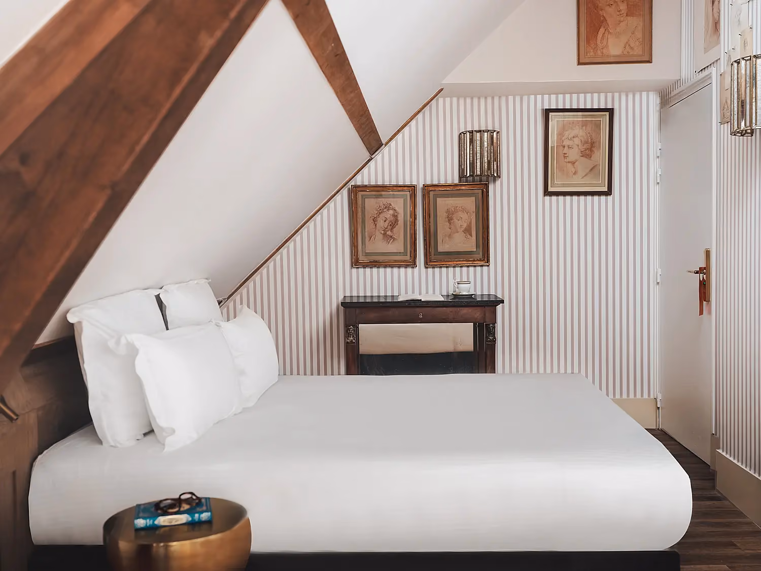 Lit double confortable dans une suite sous les toits avec décoration classique.