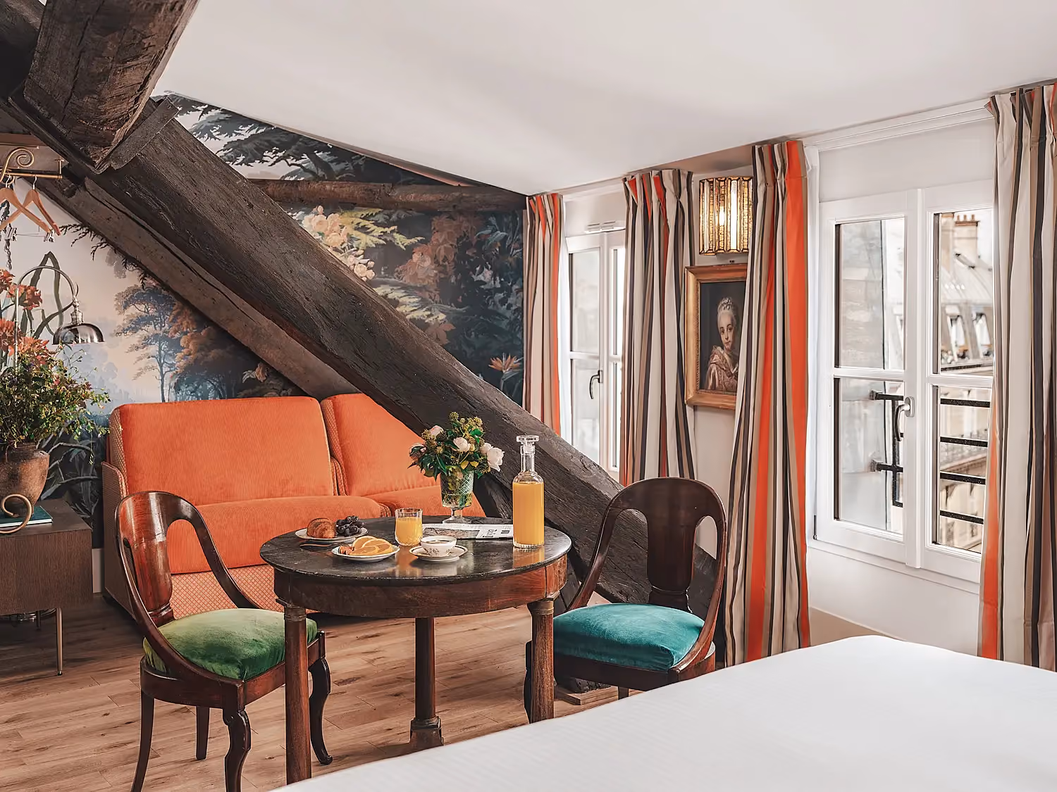 Espace salon avec canapé orange et table de repas dans une suite.