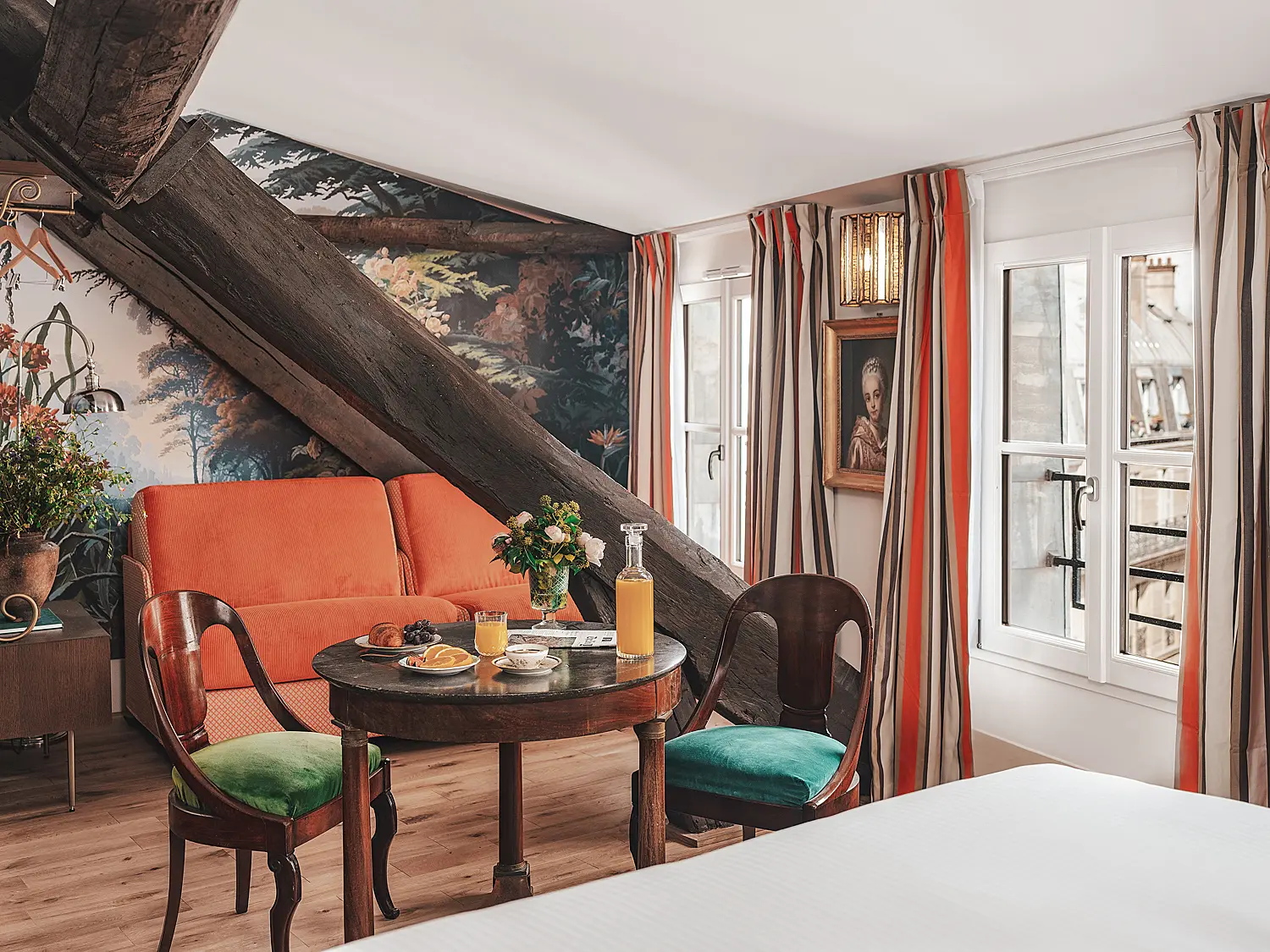 Espace salon avec canapé orange et table de repas dans une suite.
