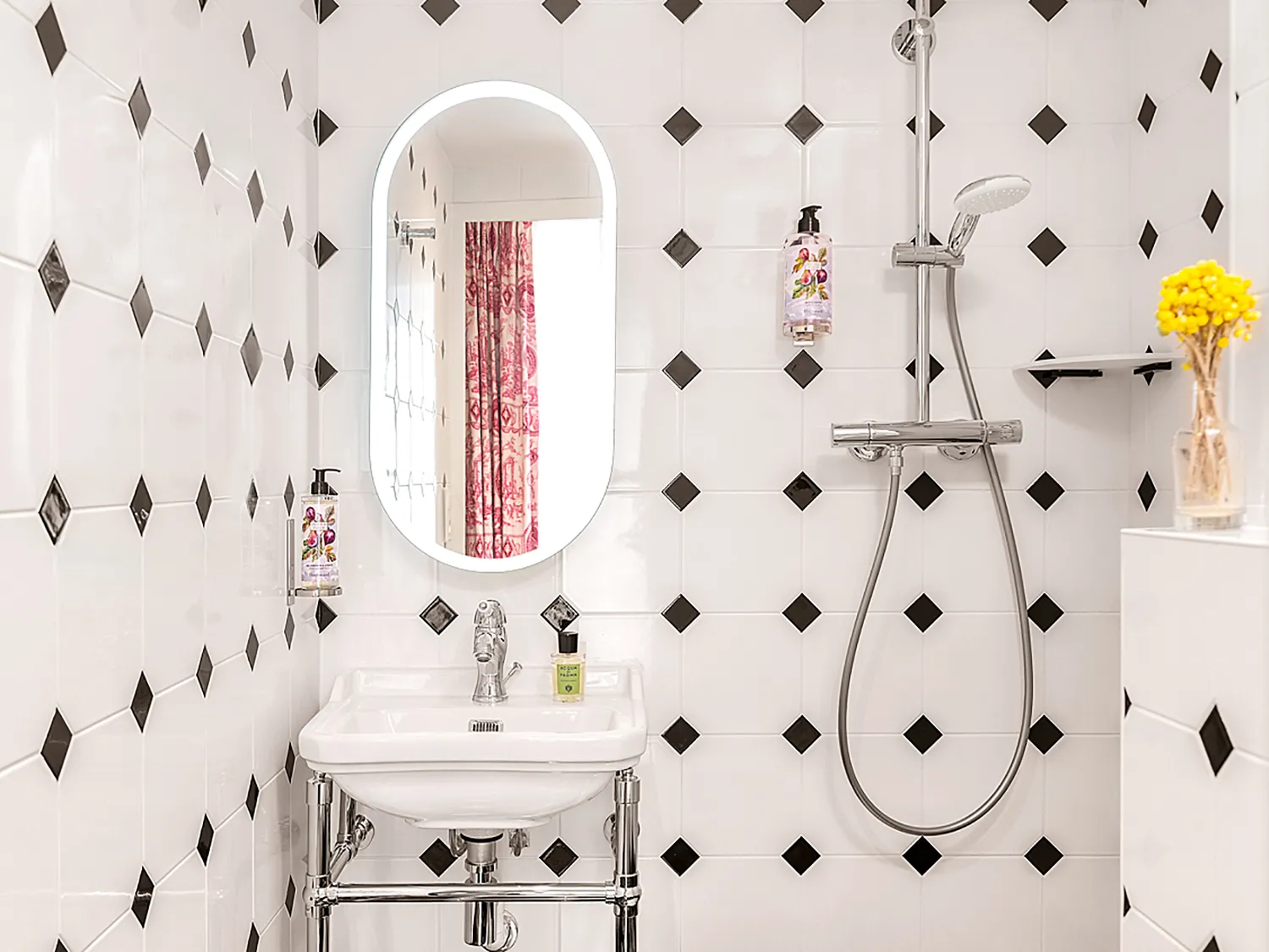 Salle de toilette lumineuse avec lavabo moderne et carrelage graphique blanc et noir.