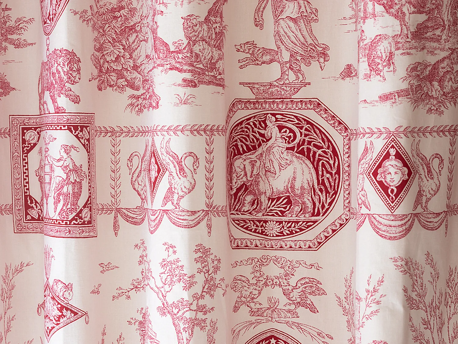 Gros plan sur un textile de style toile de Jouy aux motifs rouges et blancs.