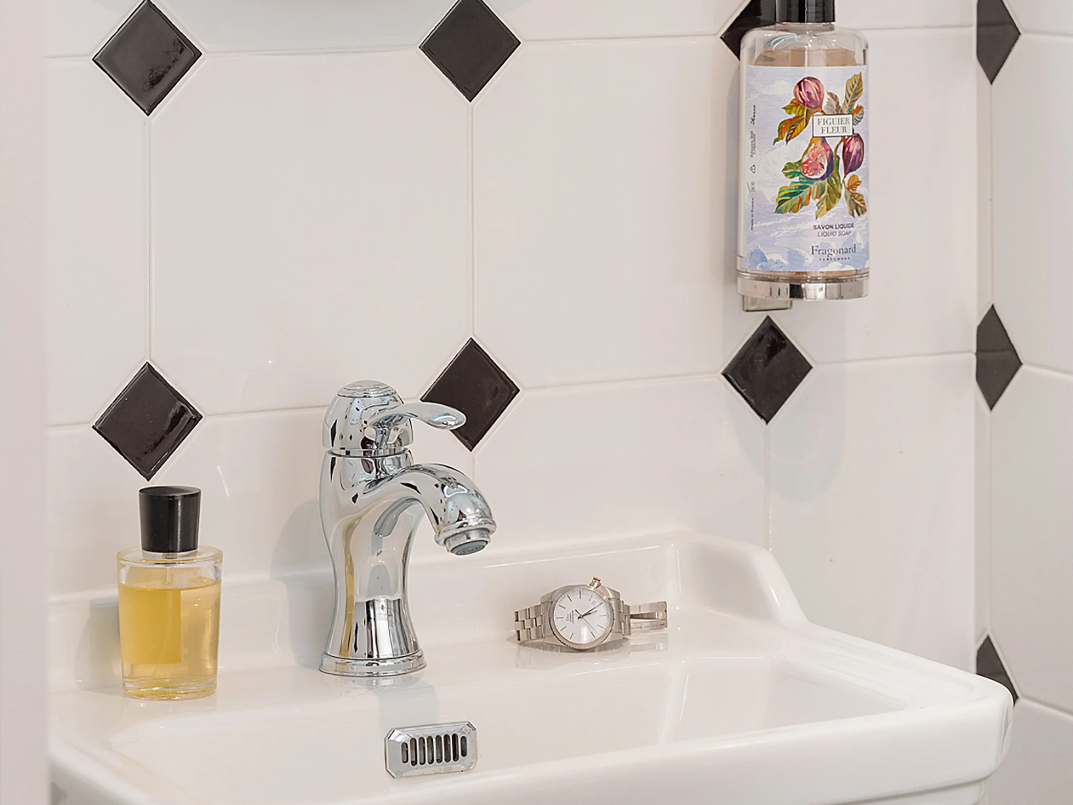Lavabo blanc avec robinetterie moderne et distributeur de savon mural.