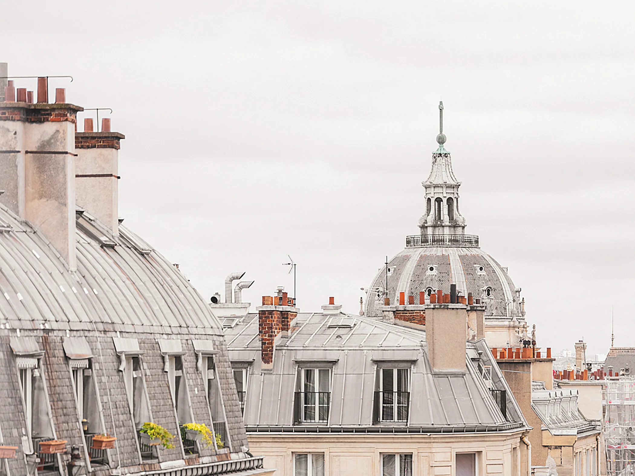 Gros plan sur les toits typiques de Paris avec un dôme en arrière-plan.