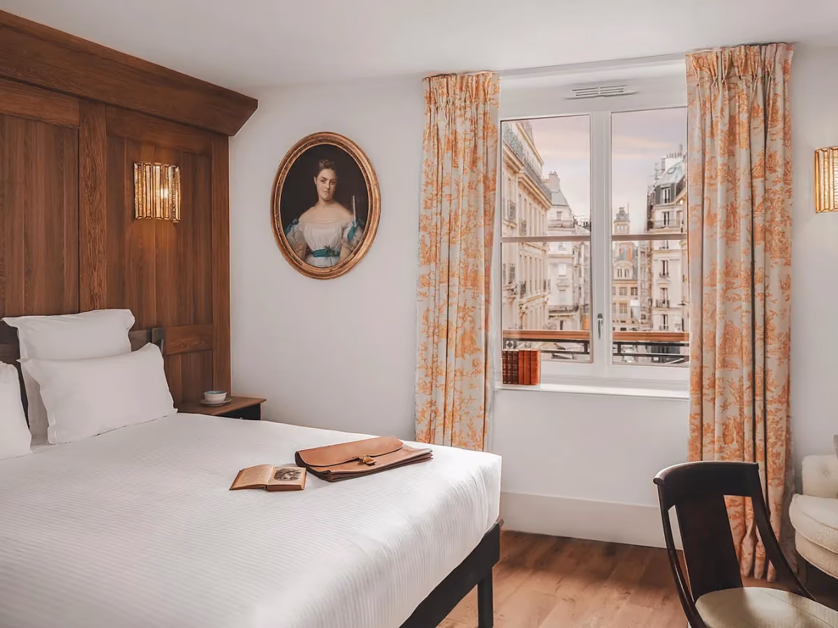 Chambre d'hôtel avec mur en bois, portrait ovale et vue sur Paris.