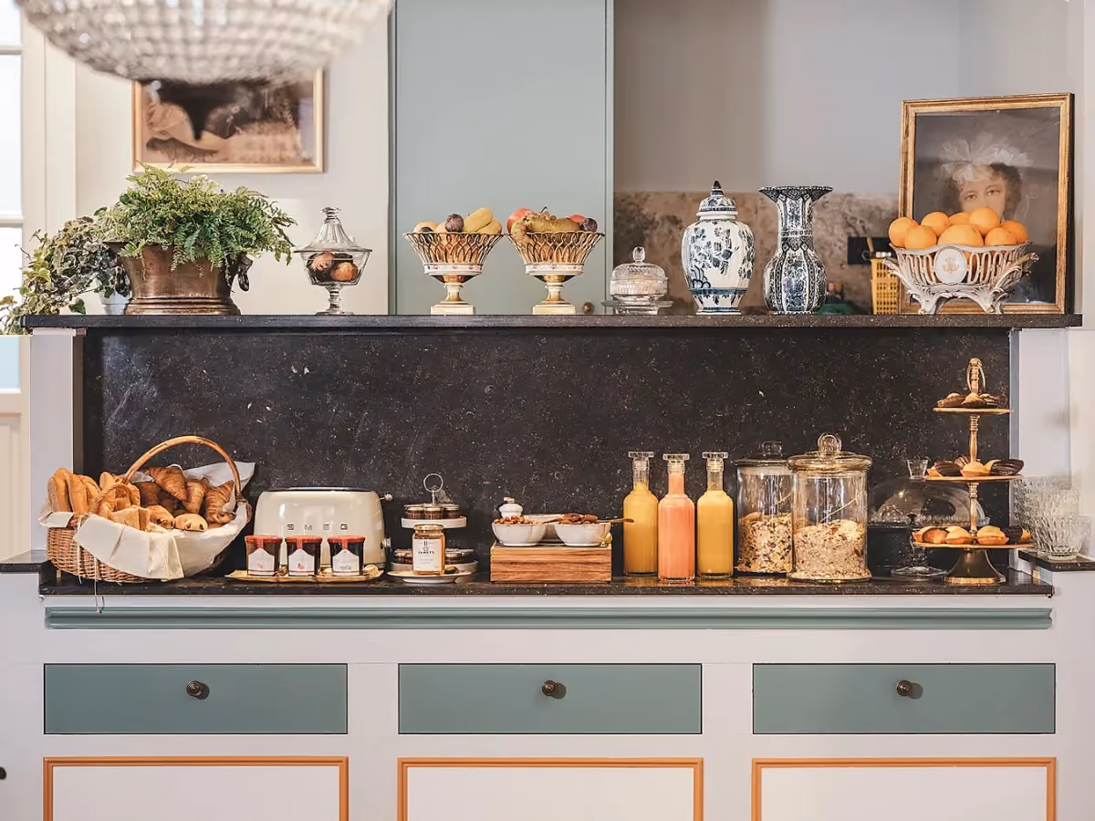 Buffet de petit-déjeuner de l’Hôtel Madeleine de Senlis, composé de pains, viennoiseries, jus, céréales et fruits décoratifs.