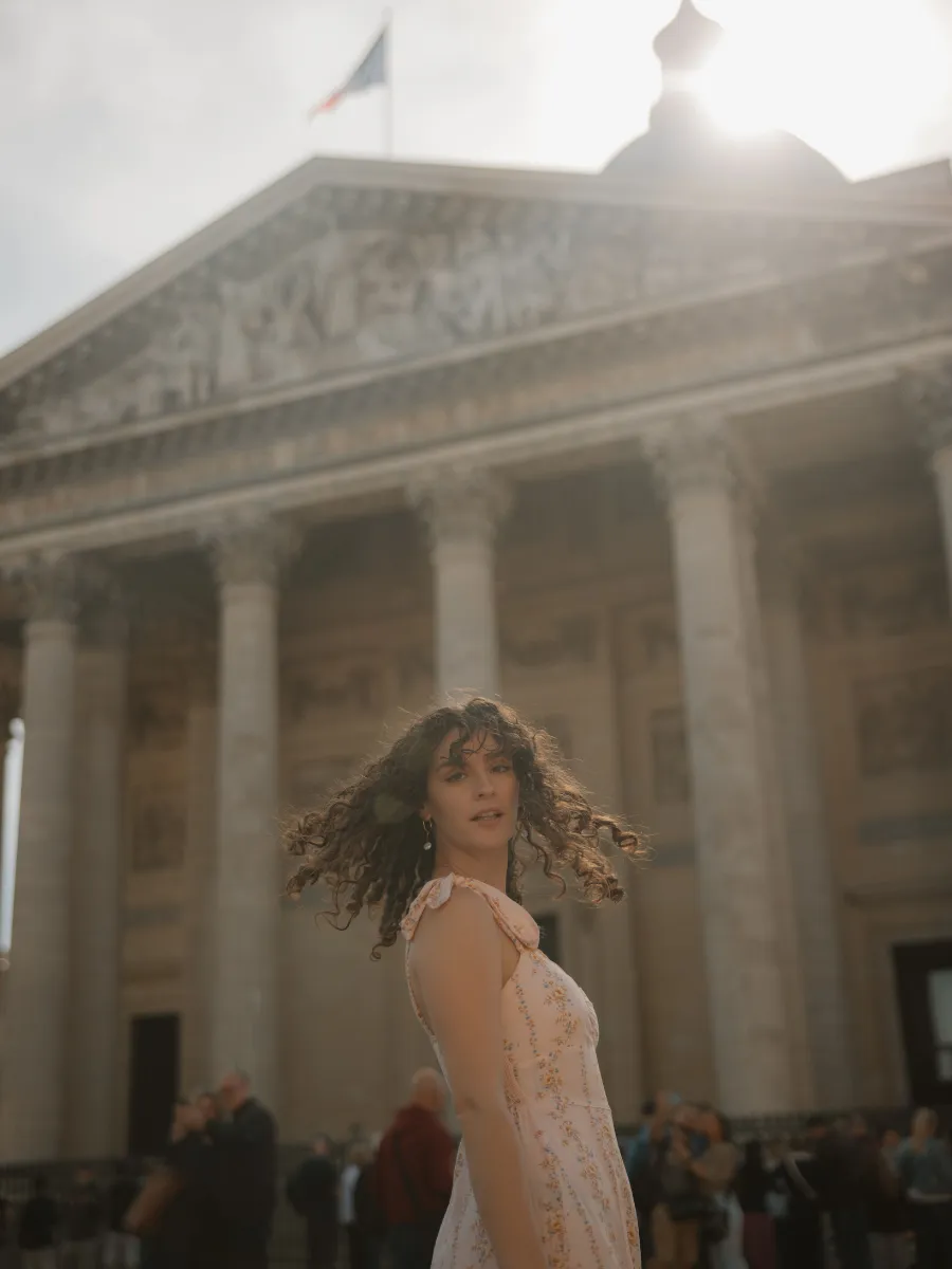 Jeune femme en robe fleurie posant devant le Panthéon à Paris.