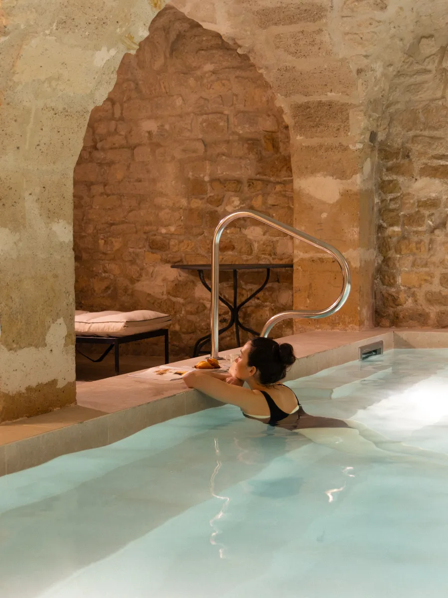 Femme se relaxant dans la piscine intérieure voûtée de l'Hôtel Madeleine de Senlis