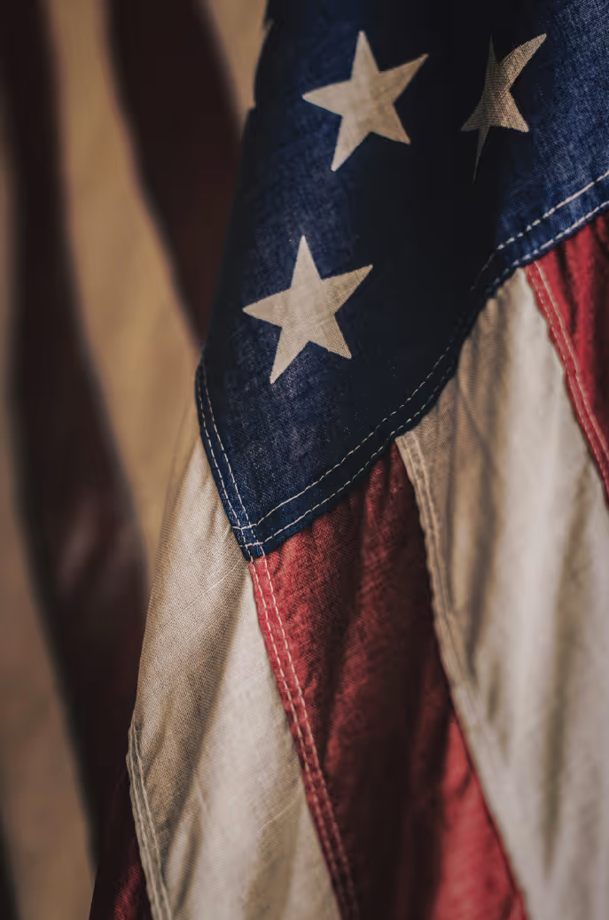 Close-up of wrinkled American flag showing white stars on blue and red and white stripes.