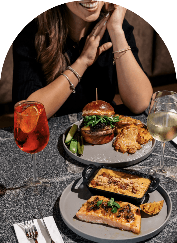 Persona sentada a la mesa con una hambrueguesa de wagyu y una bebida de especialidad