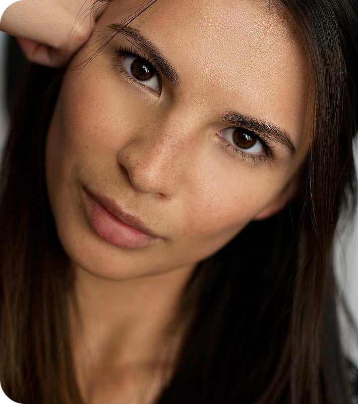 Close-up portrait of a woman with brown eyes and long dark hair looking into the camera.