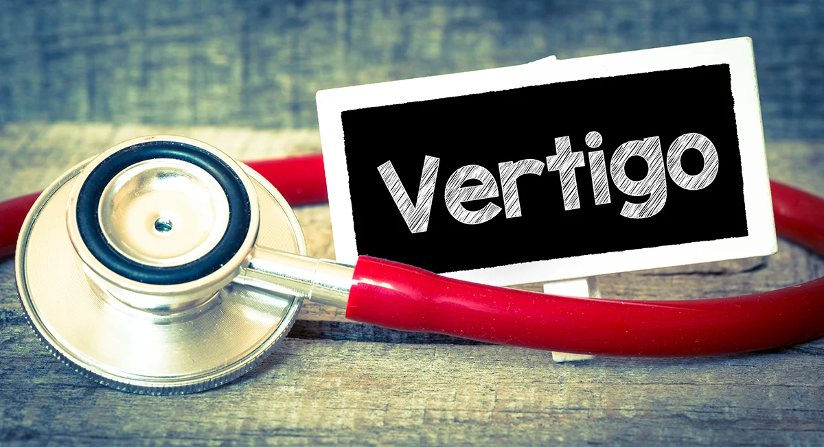 Red stethoscope on wooden surface with a sign reading Vertigo