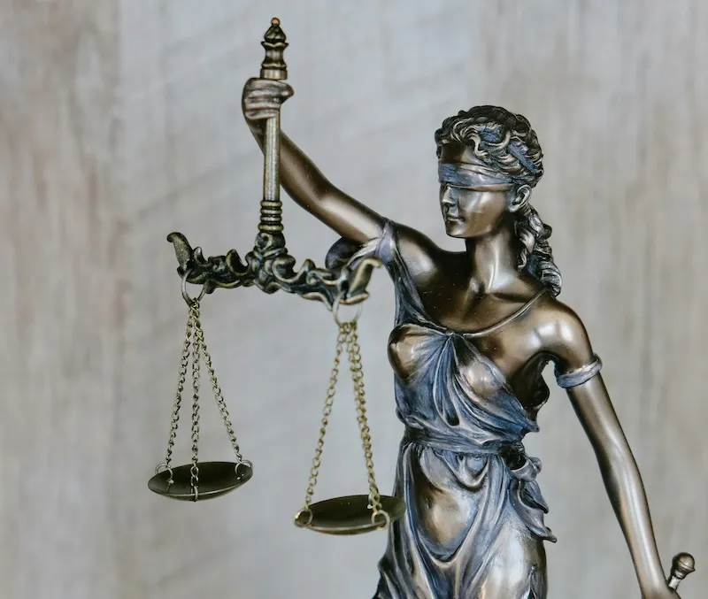 Statue der Justitia mit verbundenen Augen und einer Waage in der Hand, Symbol für Gerechtigkeit.