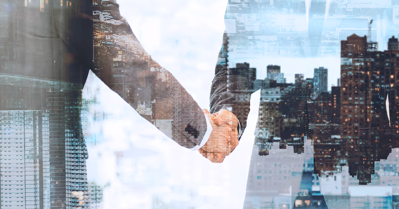 Two businesspeople shaking hands with a double exposure of a city skyline.