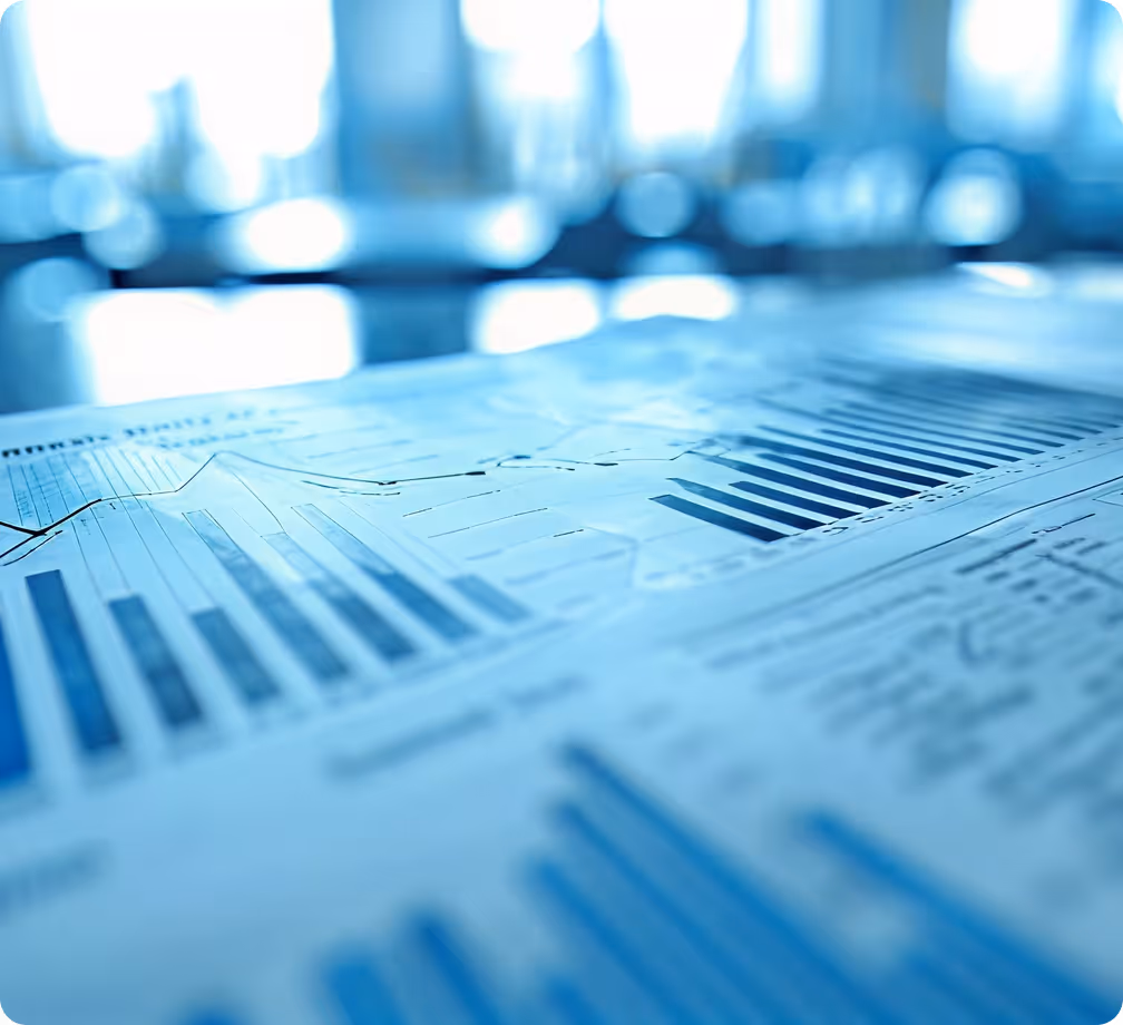 Close-up of printed financial charts and bar graphs on a desk with a blurred blue-toned background.