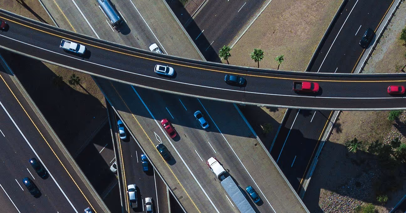 Aerial view of a busy highway interchange with multiple lanes and vehicles including cars and a truck.