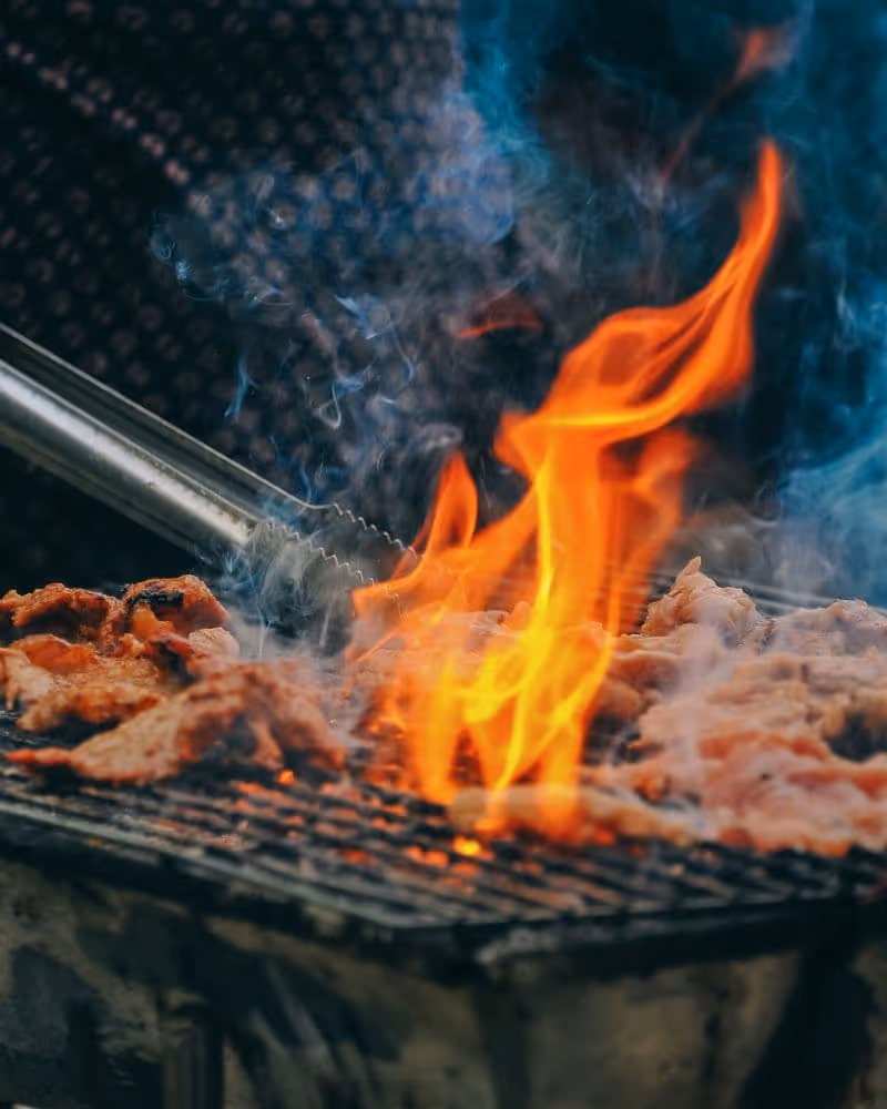 Vlees op de grill met open vuur tijdens een zakelijk BBQ buffet door De Keukenploeg