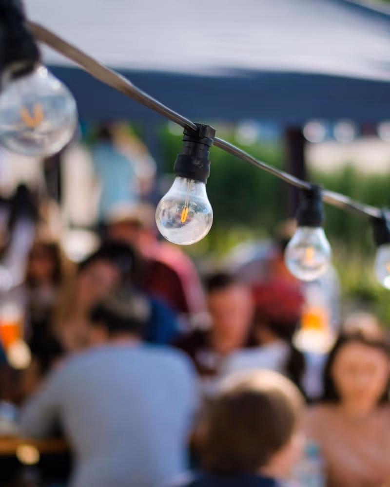 Gasten genieten samen van een zakelijk BBQ buffet buiten met sfeerlichten