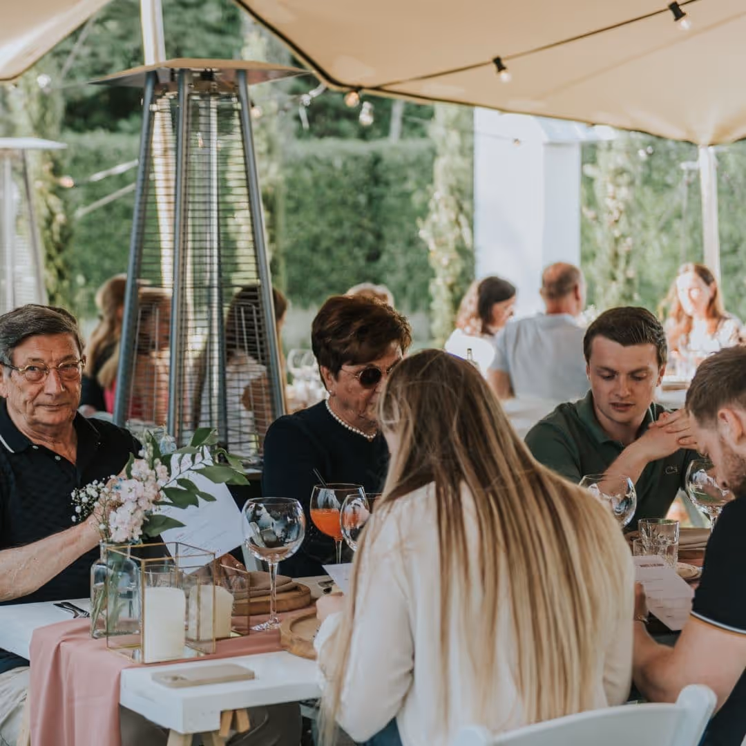 Gasten aan tafel onder een tent tijdens een feestelijk buiten evenement van De Keukenploeg