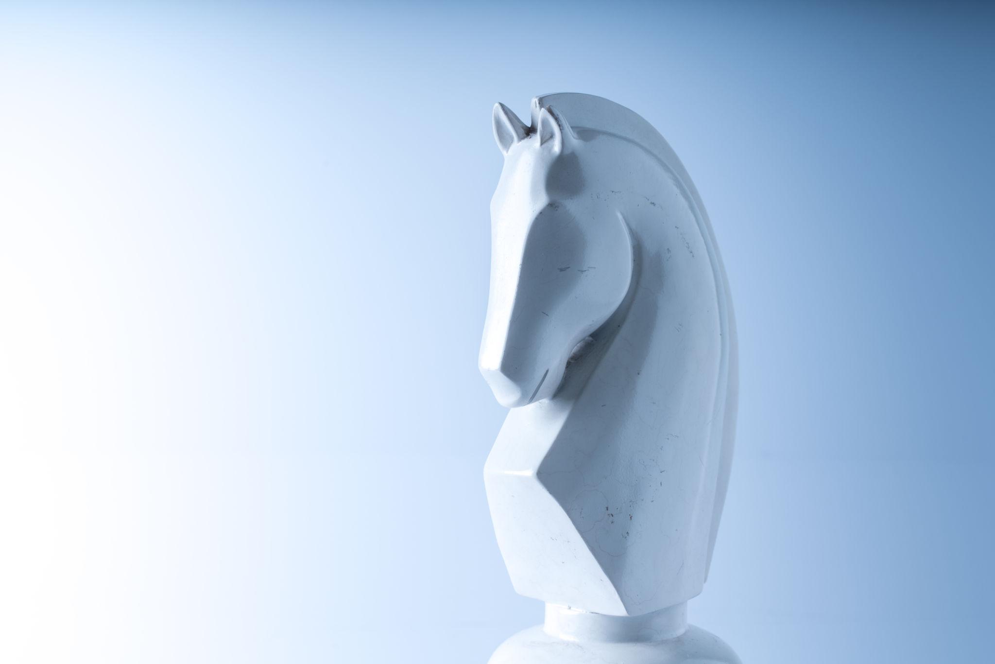 Pièce d'échecs cavalier blanc en gros plan sur fond dégradé bleu.