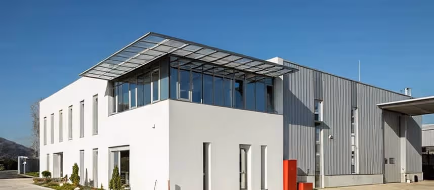 Modern industrial building with white and gray exterior walls under a clear blue sky.