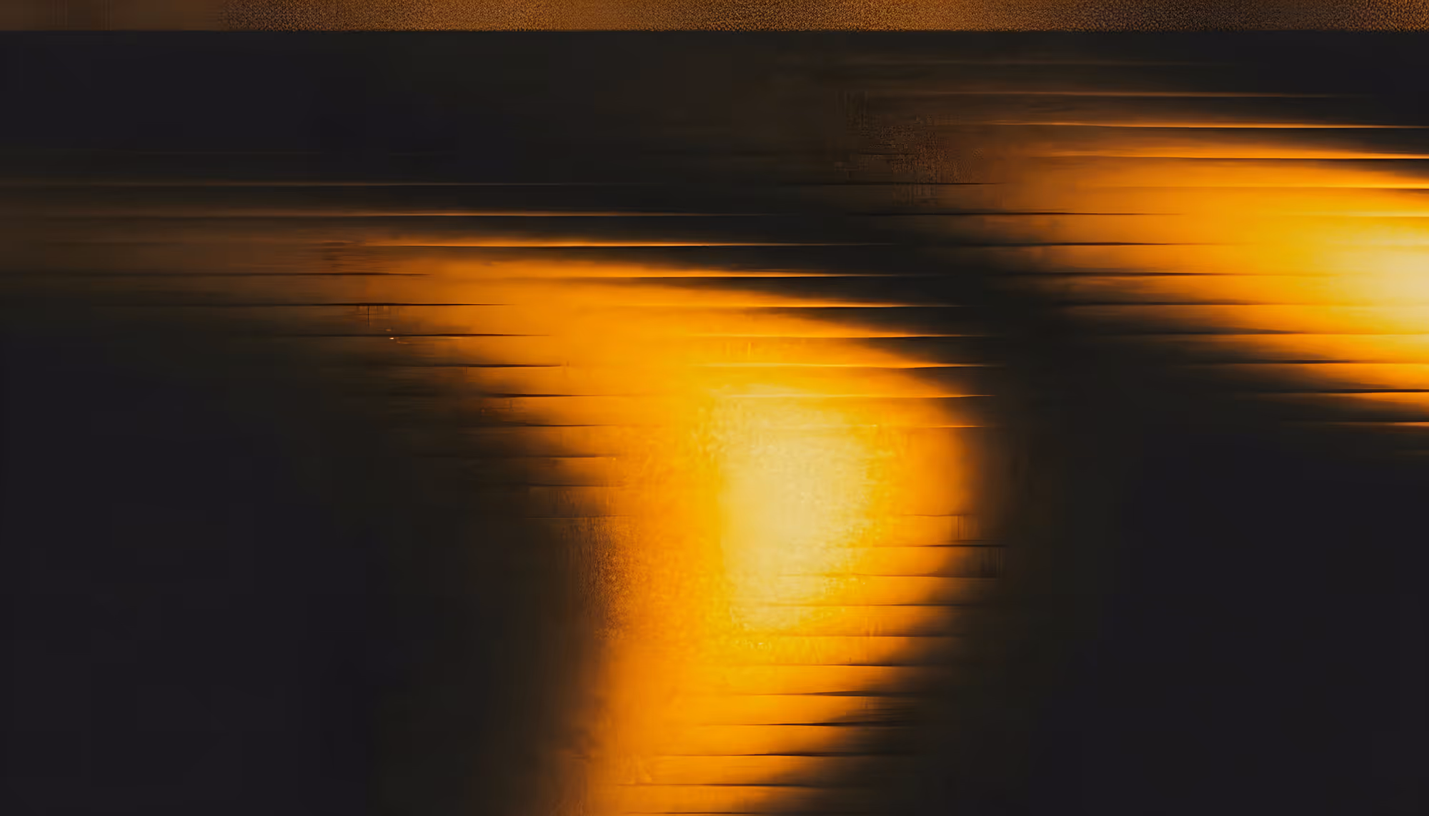Abstract motion-blurred image of a golden sunset reflected on water, with horizontal streaks of amber and orange light against a dark background, creating a dreamlike, glitchy effect.