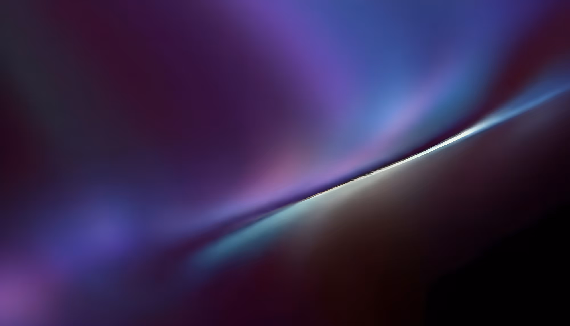 Abstract diagonal light streak cutting across the image from lower-left to upper-right, with deep purple and blue tones in the upper portion fading to dark maroon and black in the lower portion, suggesting motion or a luminous edge against a dark background.