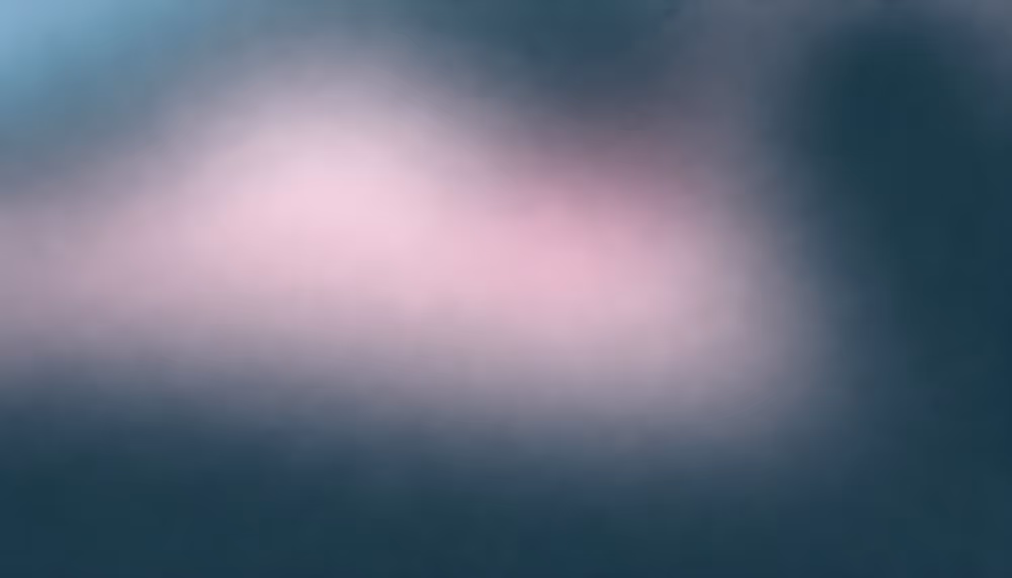A blurred, abstract image with soft gradients of pink and teal, creating a dreamy, serene mood. The colors blend seamlessly without distinct shapes.