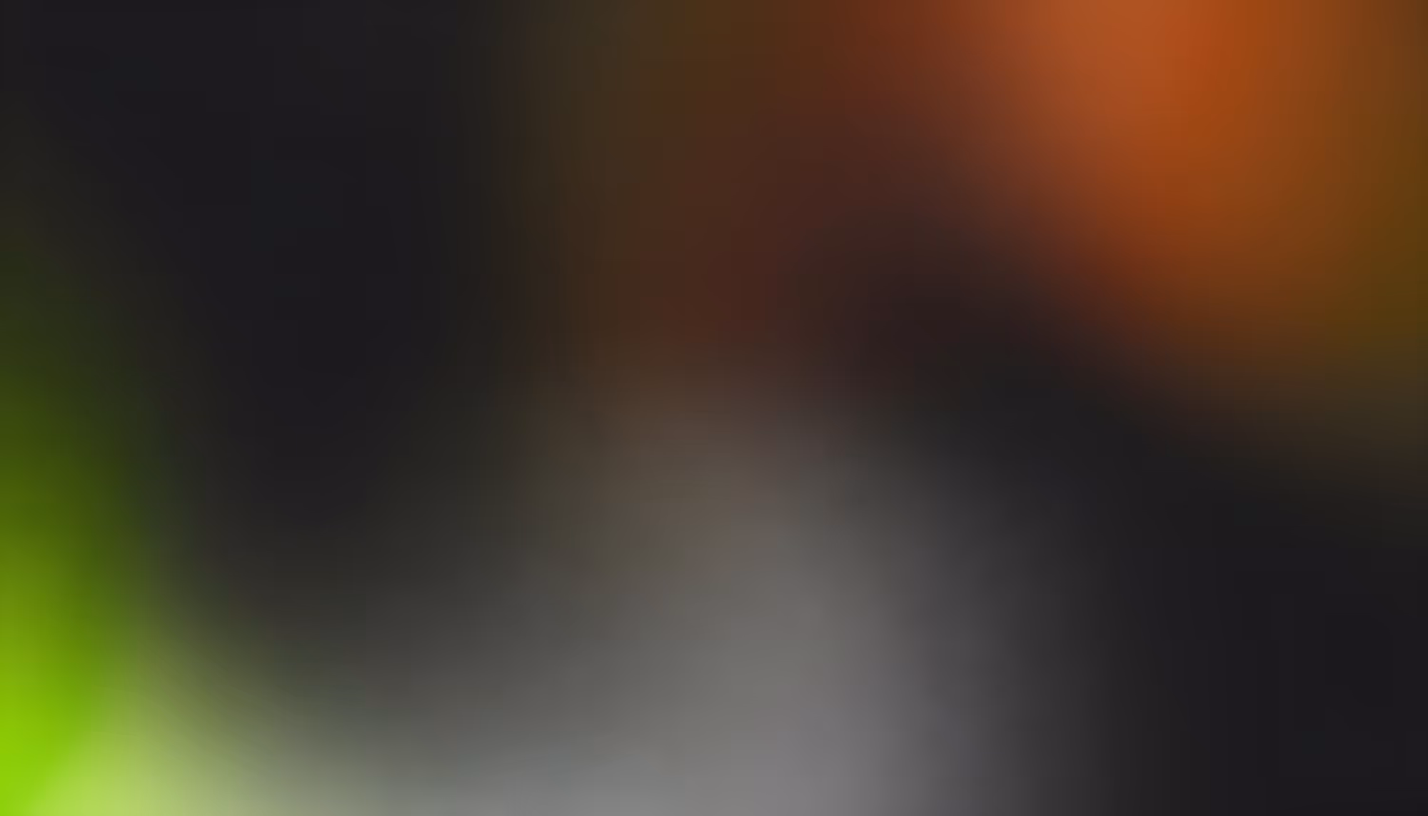 A soft, out-of-focus blend of colors with a dominant black background, featuring hints of green on the left and warm orange tones on the top right.