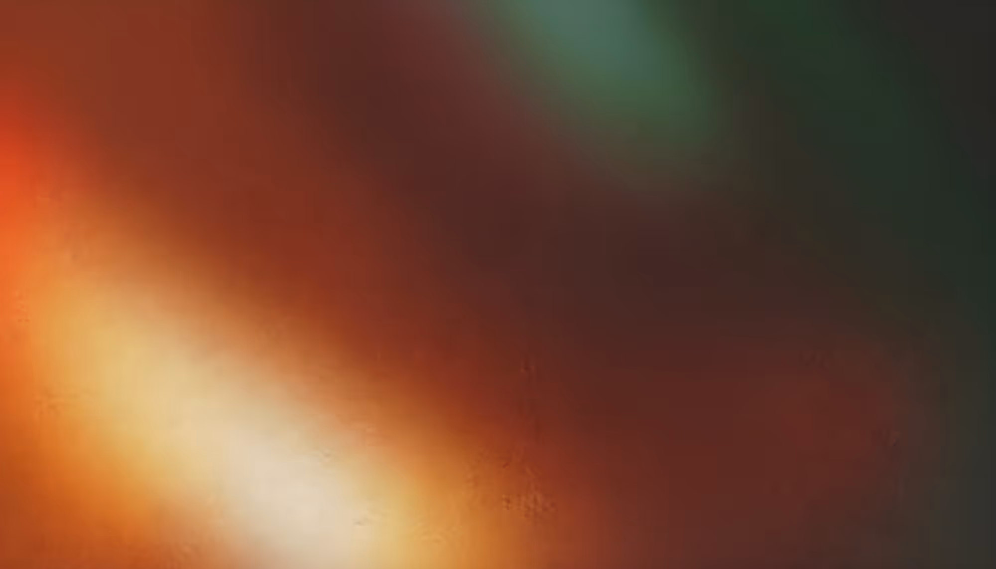 Abstract image with warm hues of red, orange, and green softly blended. The colors create a smooth, calming gradient with a glowing effect.