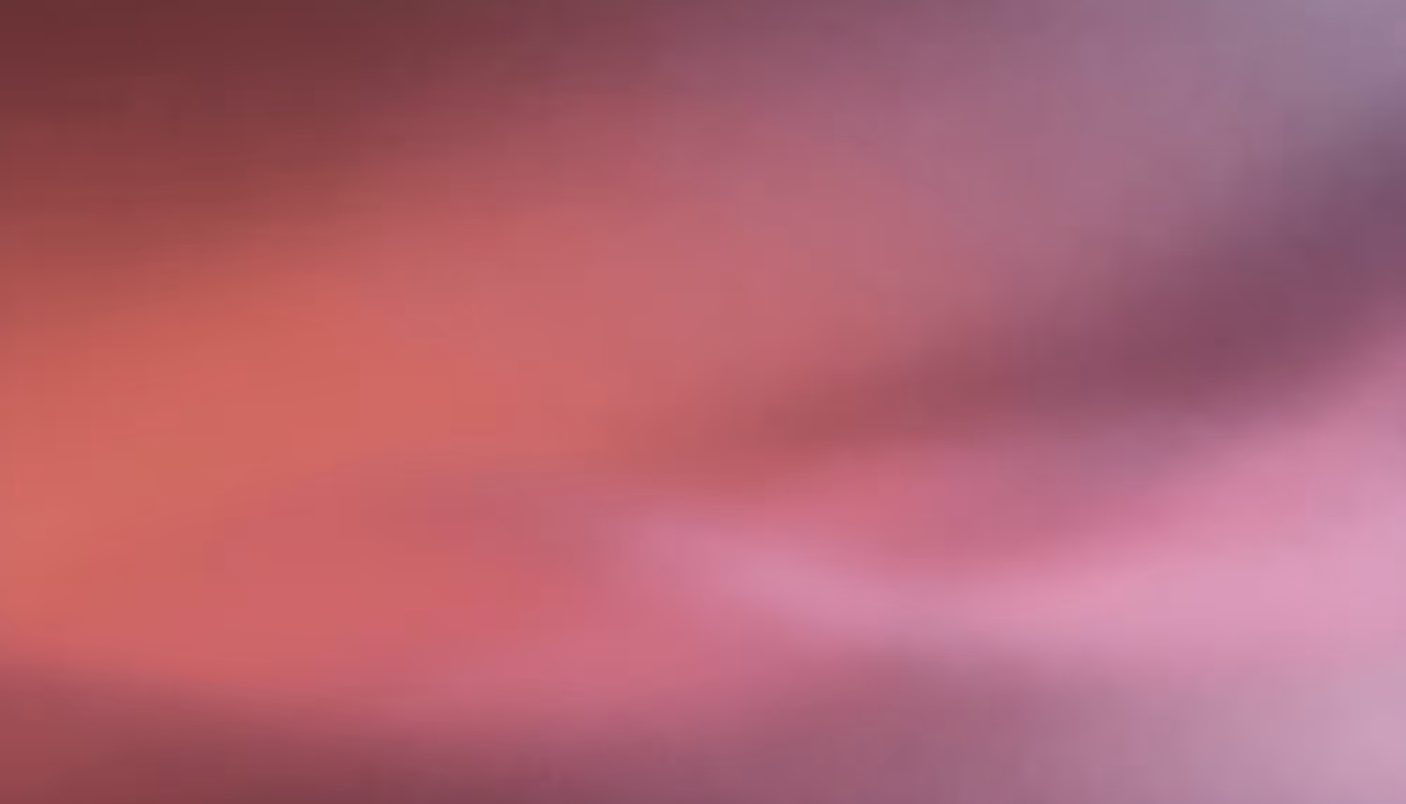 Abstract image with warm hues of red, orange, and green softly blended. The colors create a smooth, calming gradient with a glowing effect.