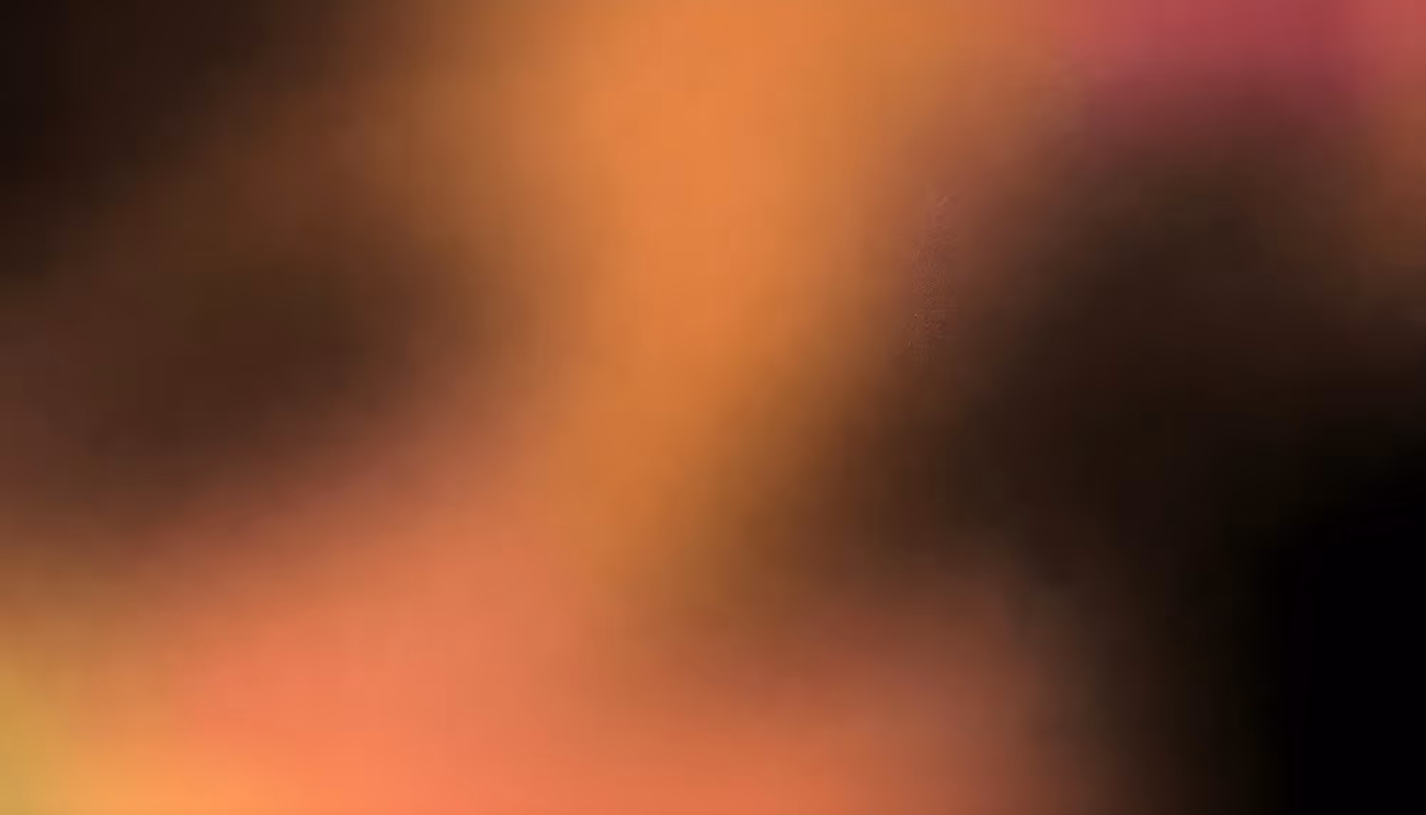 Abstract image with a gradient of warm hues blending from black to orange, pink, and yellow, creating a soft, blurred effect with a serene tone.