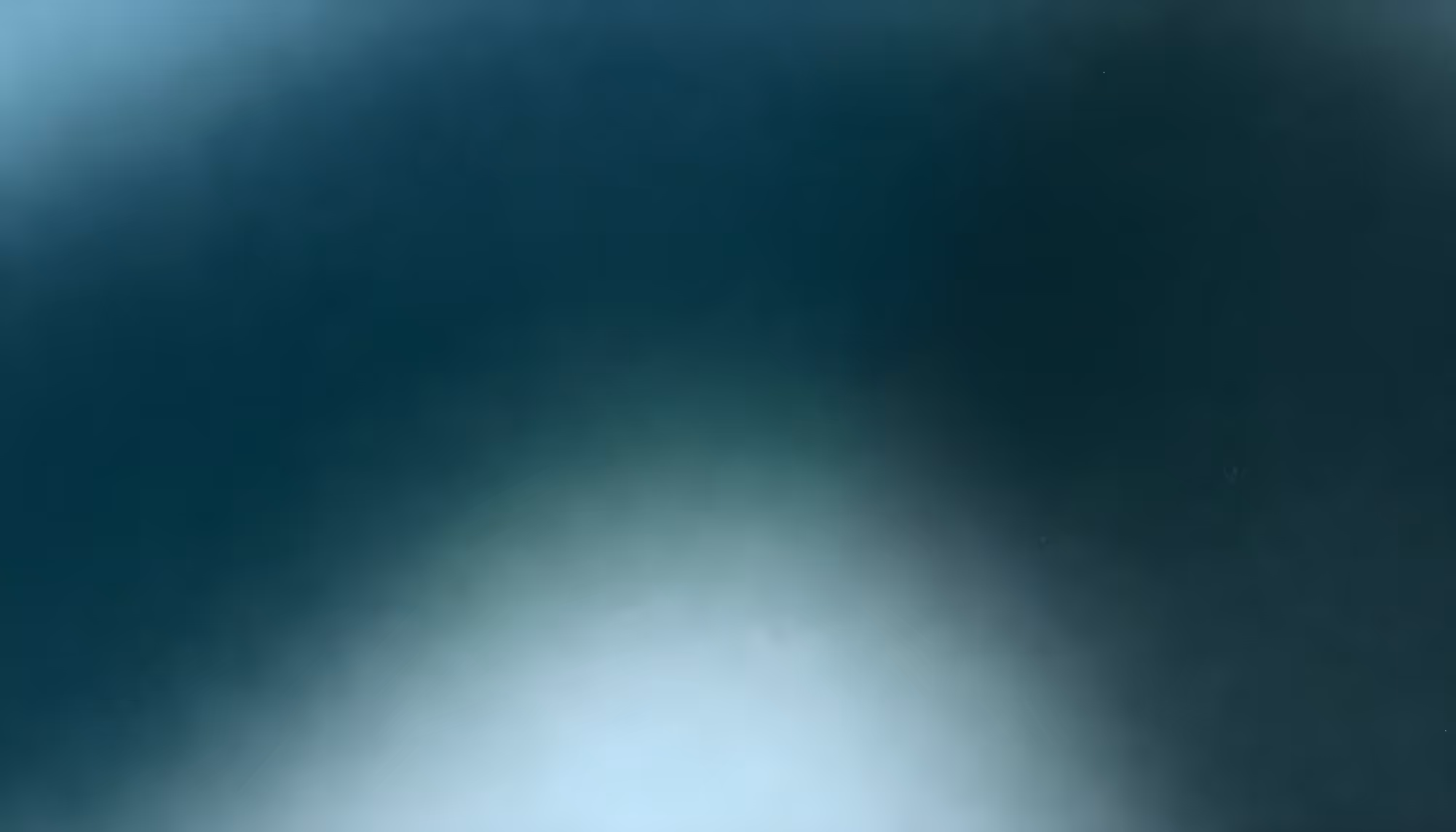 A blurred, abstract image featuring a gradient of dark teal at the top, blending smoothly into a lighter teal and white toward the bottom.