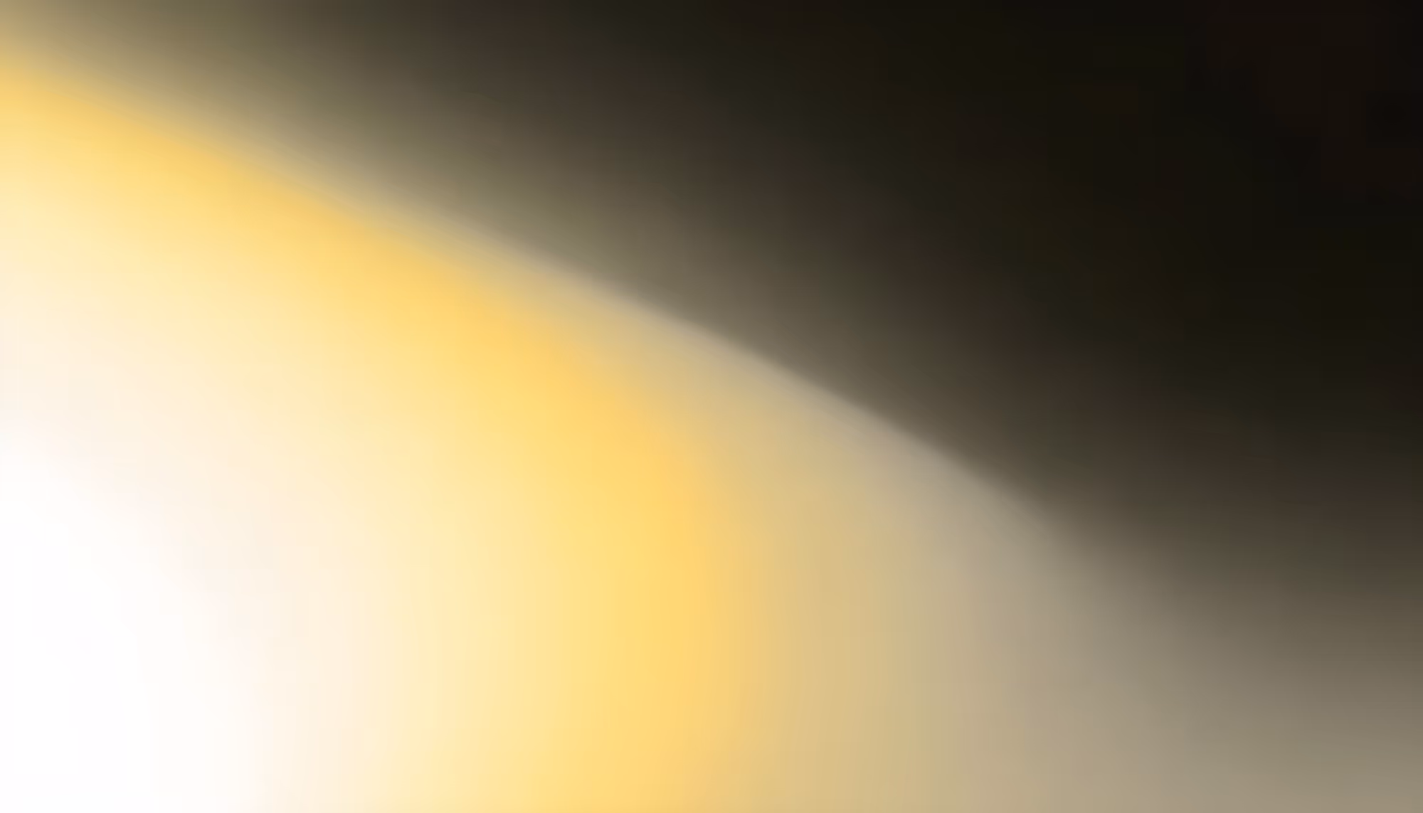 A blurred abstract image with a gradient of soft yellow and white transitioning to dark gray. The effect conveys a calm, serene atmosphere.