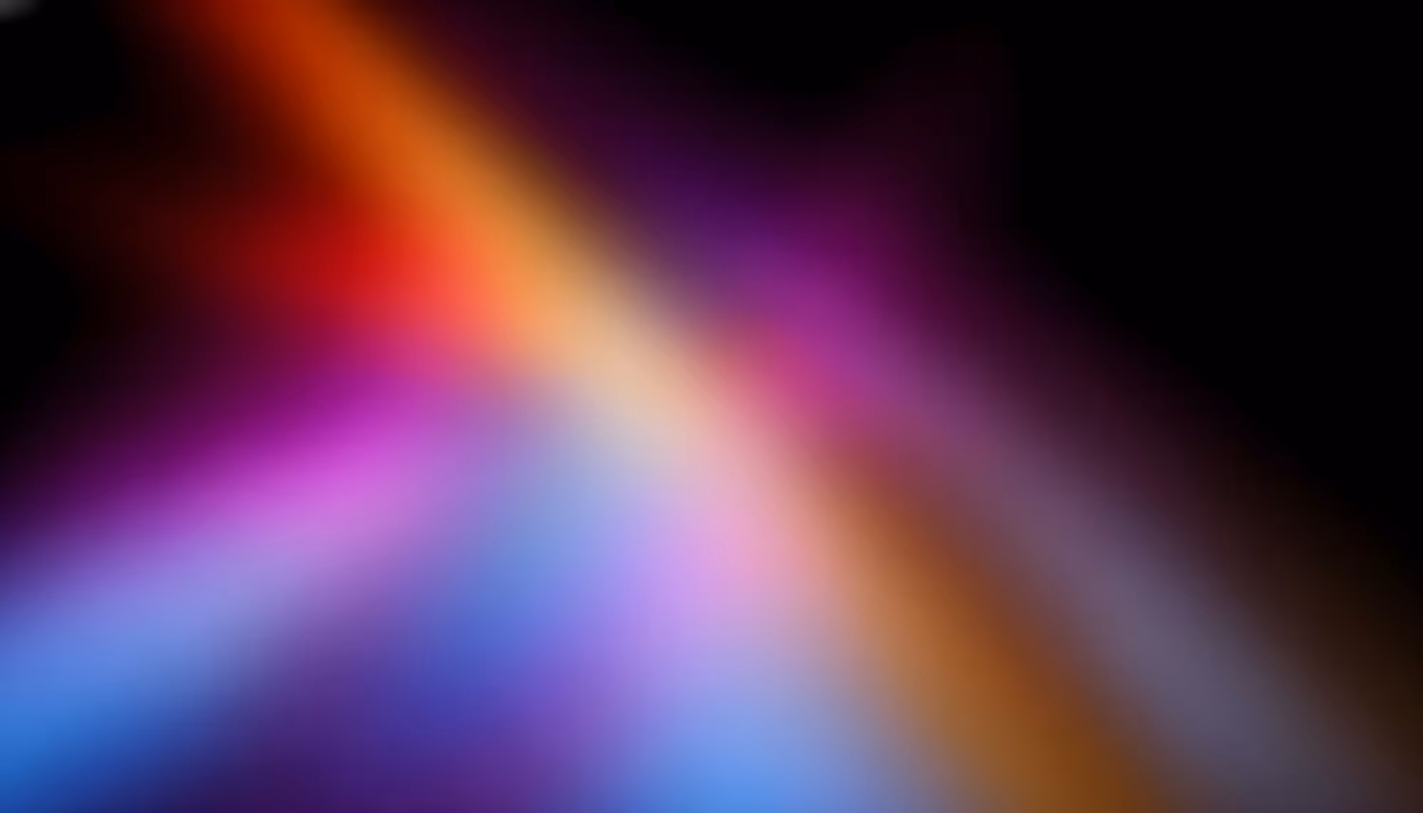 Abstract image featuring vibrant, blurred streaks of red, orange, purple, and blue against a black background, evoking a sense of energy and motion.
