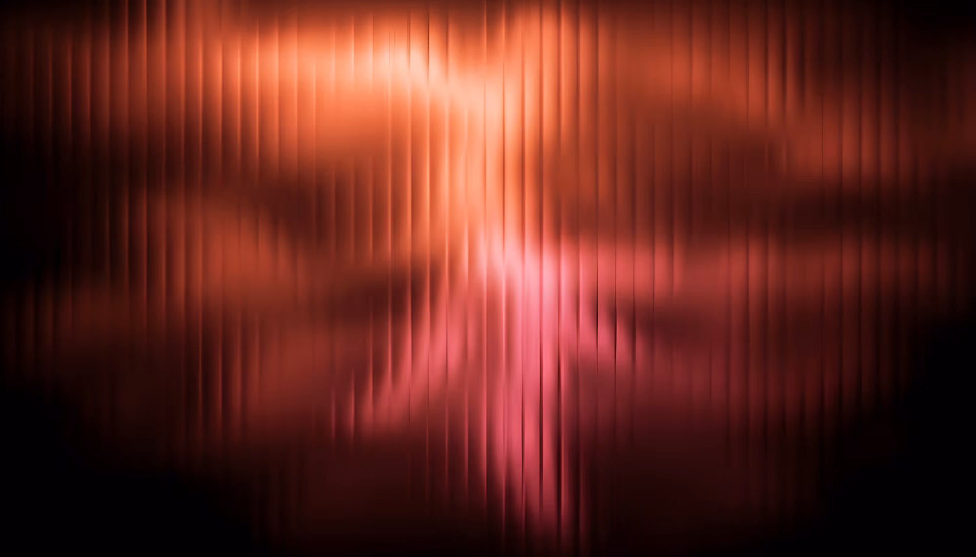 A blurred image with vertical lines in shades of red and pink. The abstract pattern creates a warm, soothing atmosphere with a soft glow.