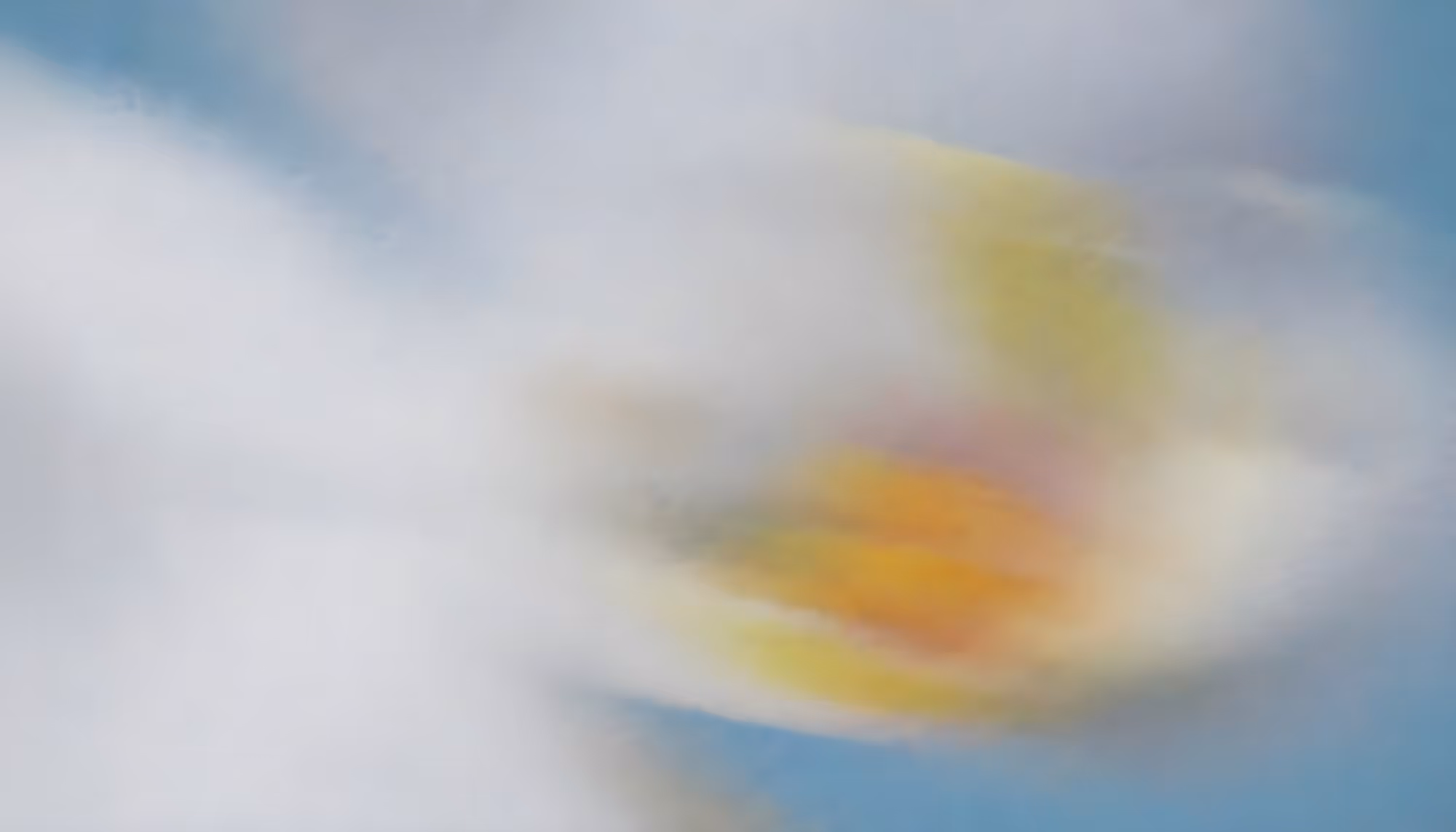 A blurred, abstract image featuring soft white and yellow hues blending into a light blue background, conveying a sense of motion and calmness.