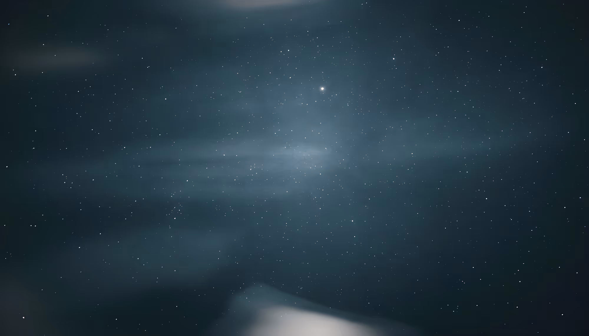 Starry night sky with a faint hazy glow in the center. A few scattered clouds add depth to the serene and expansive celestial scene.