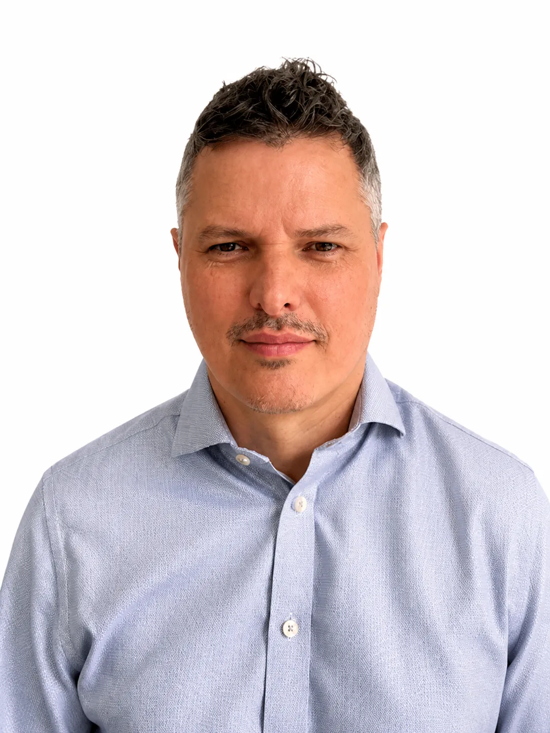 Man with short dark gray hair and mustache wearing a light blue button-up shirt against white background.