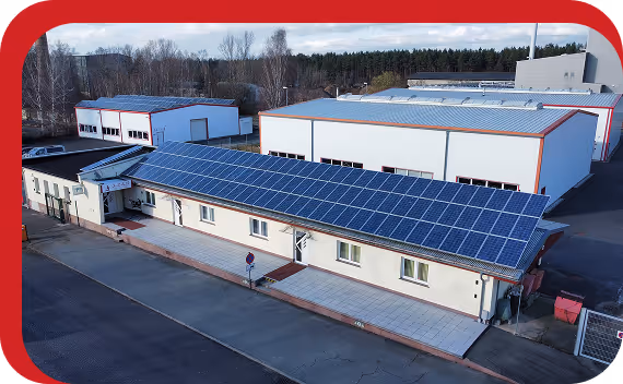 Gebäude mit einer großen Fläche von Solarmodulen auf dem Dach in einem Industriegebiet.