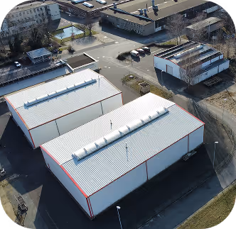 Luftaufnahme von zwei weißen Lagerhallen mit roten Kanten in einem Industriegebiet.