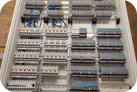 Geöffneter Verteilerkasten mit mehreren Reihen von Sicherungsautomaten und elektrischen Drähten.